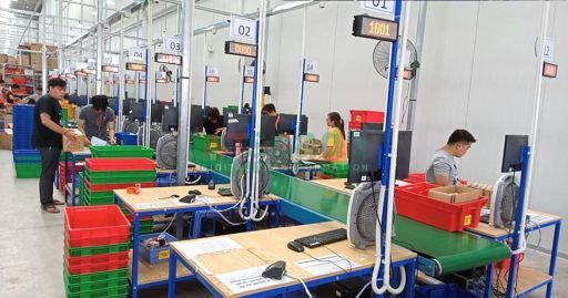Manufacturing production line with workers and assembly stations using production monitoring system in factory