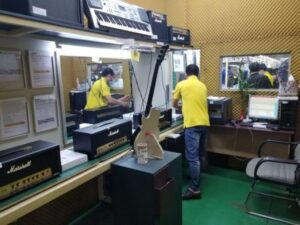 Factory operator using industrial machine with digital monitoring screens displaying real-time production data in manufacturing workshop
