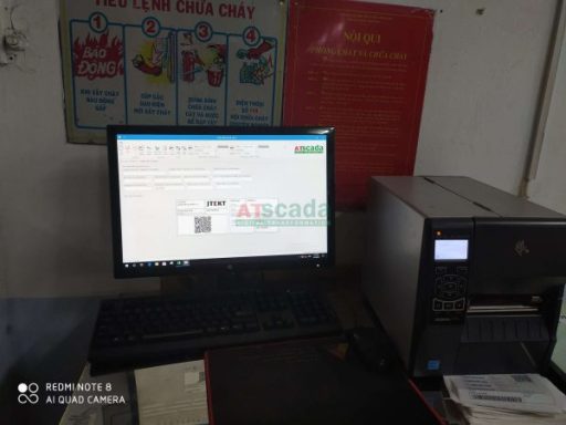 Industrial workstation with computer and printer running SCADA monitoring software for real-time factory data management and reporting